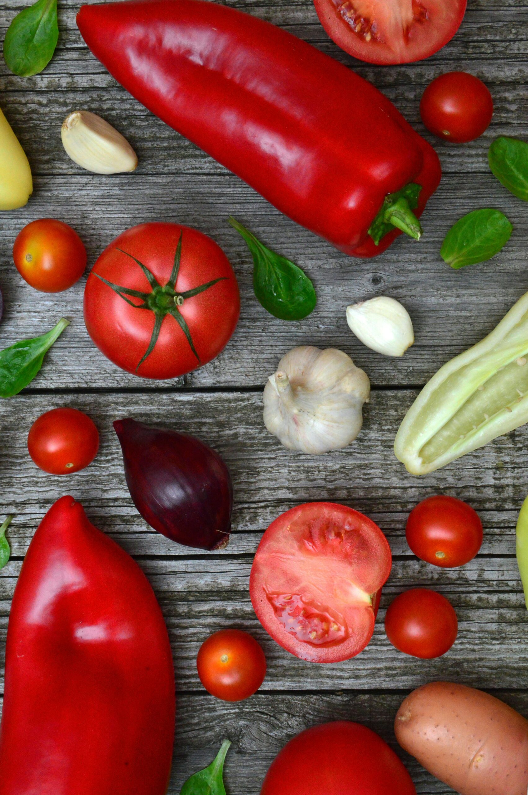 #FeedingVermontTogether Vibrant fresh vegetables including tomatoes, peppers, and garlic on a rustic wooden surface.